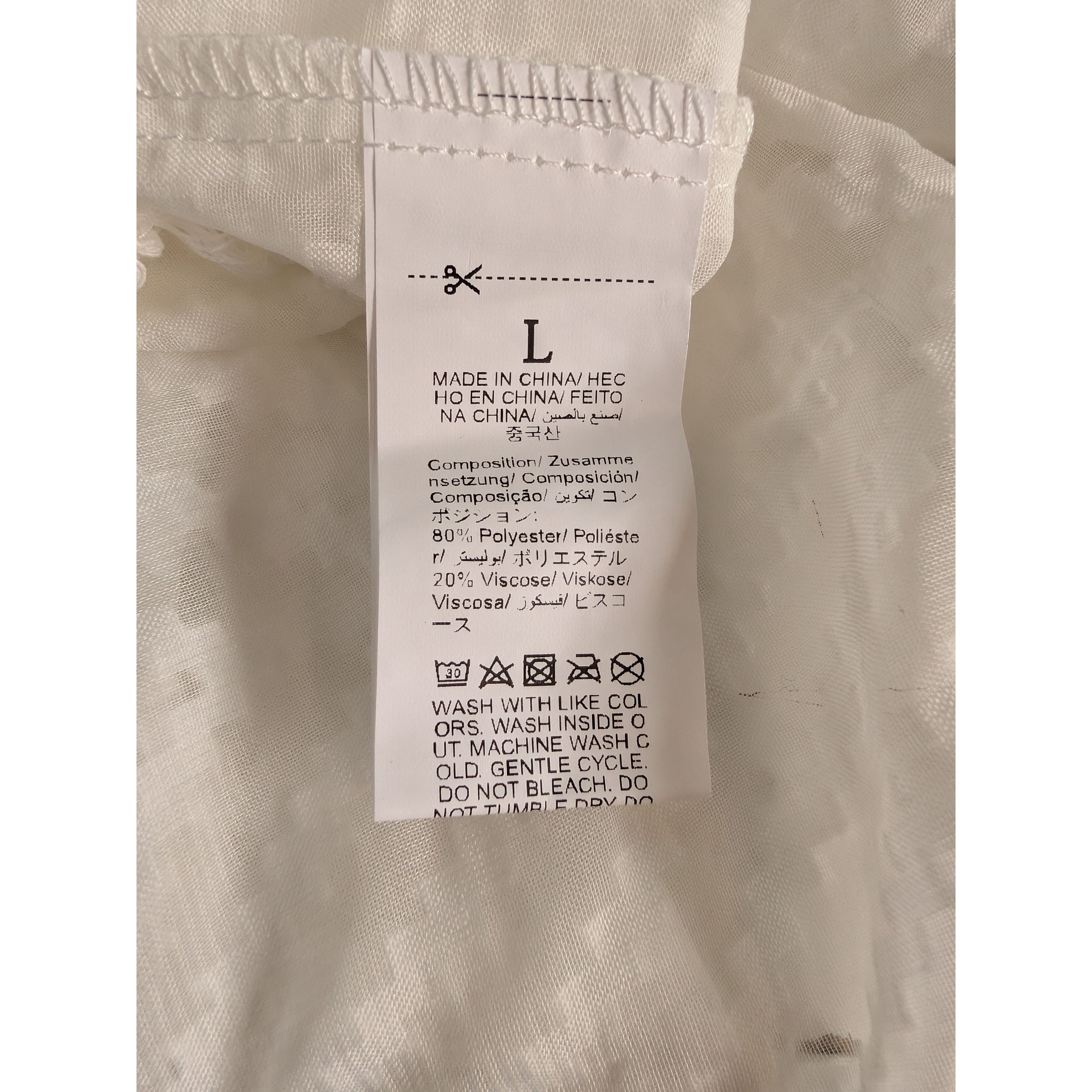 Fabric tag on a beige garment with text and symbols.