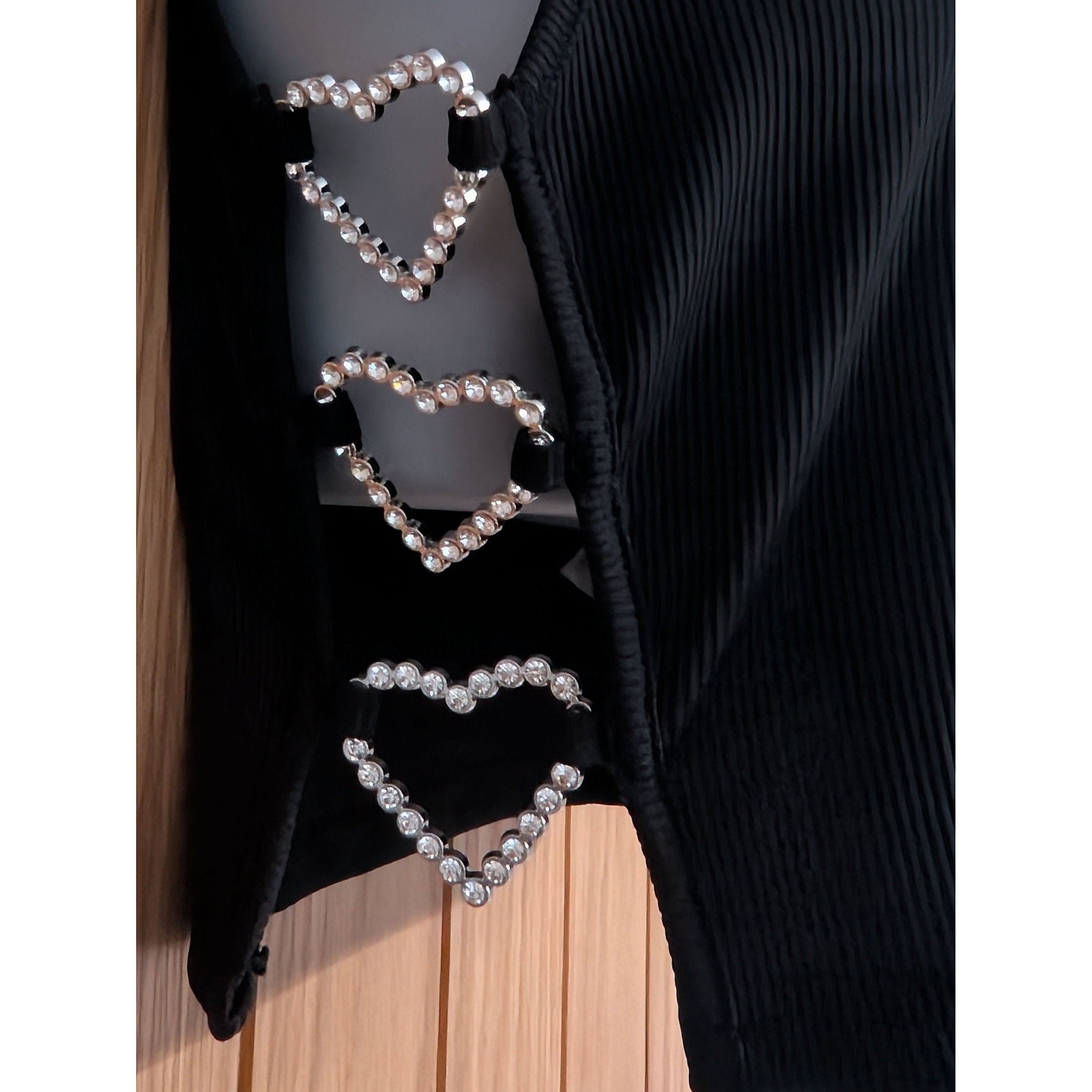 Black garment with pearl heart designs on a wooden surface