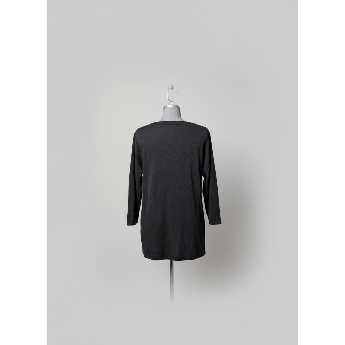 Dark gray long-sleeve shirt on a mannequin against a tiled wall.