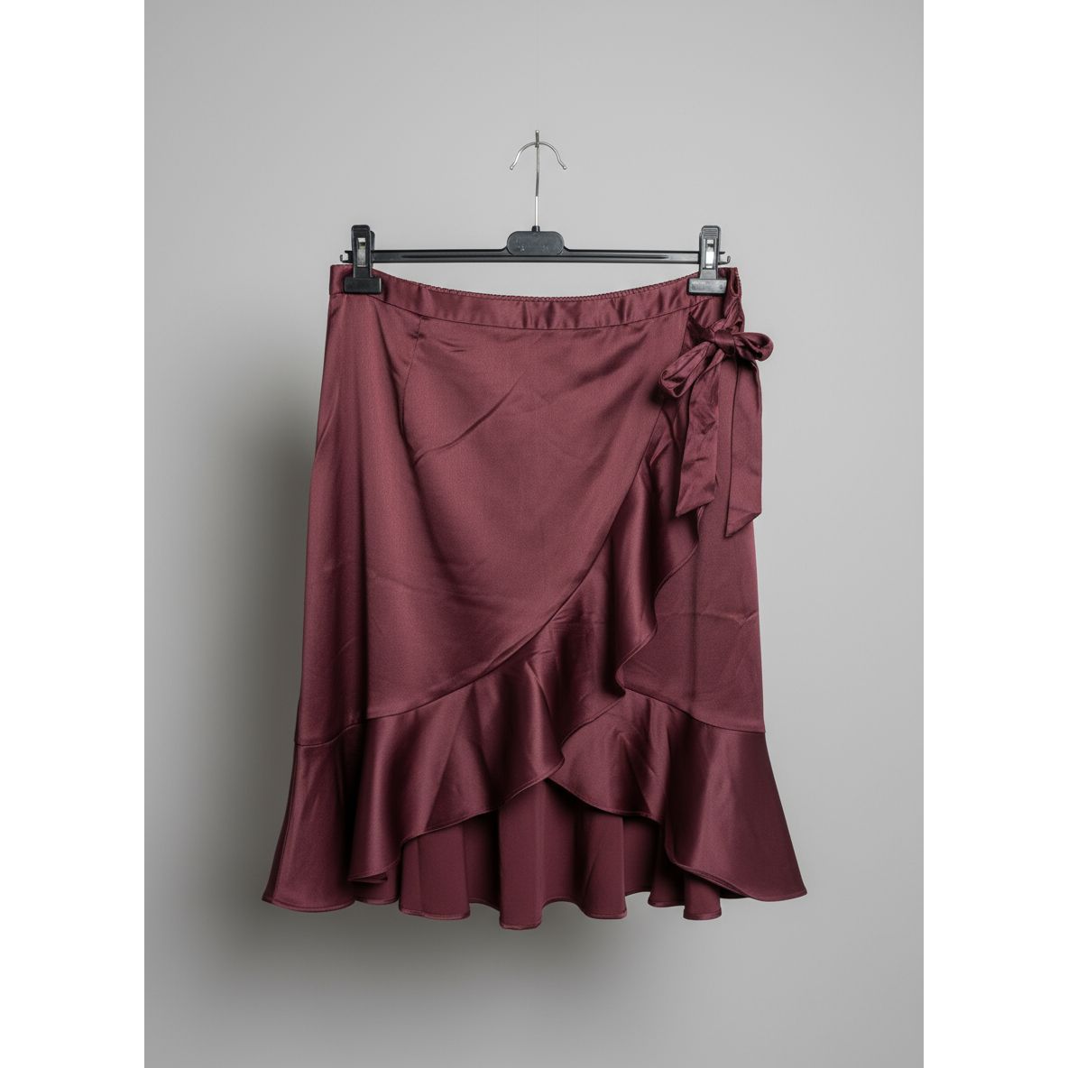 Maroon satin skirt draped over a stove with a tiled wall background