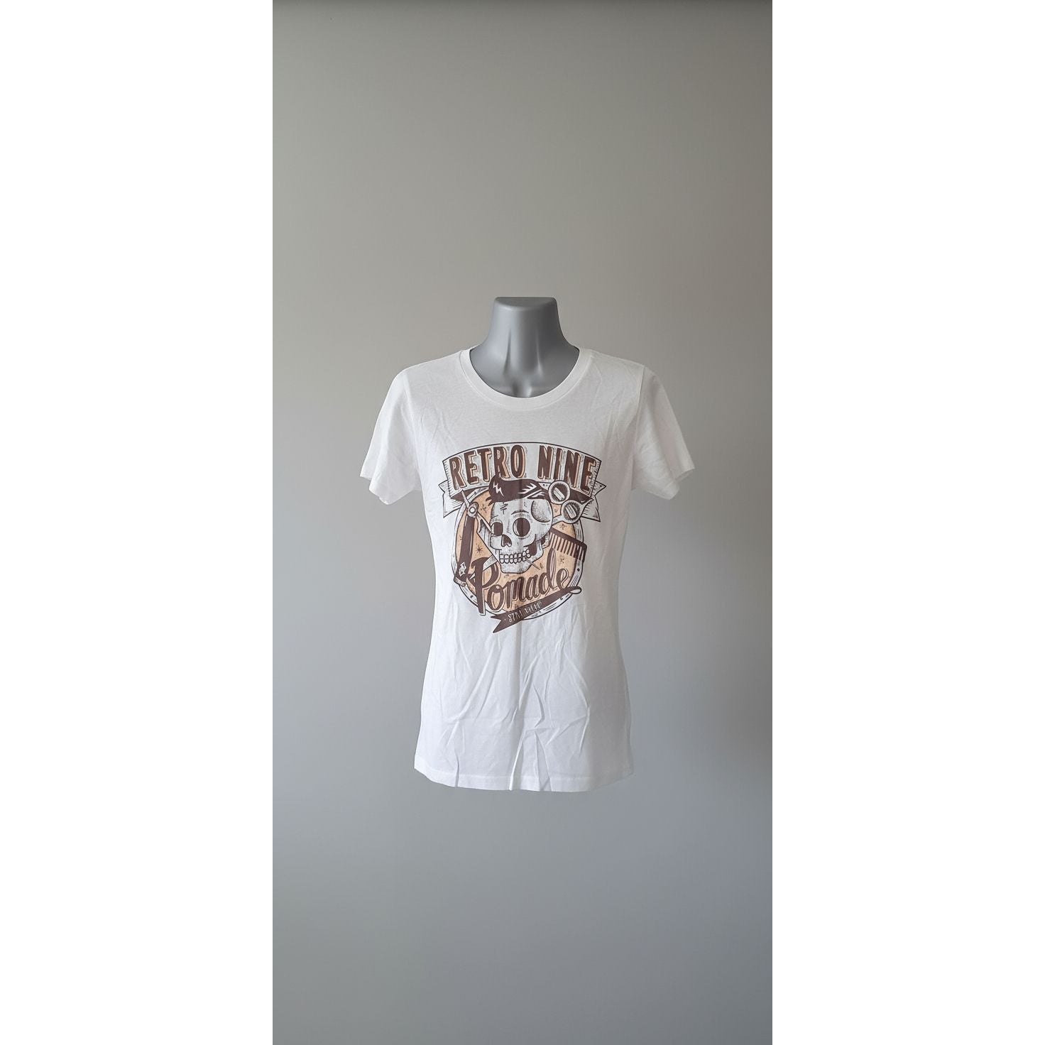 White t-shirt with brown graphic design on a mannequin against a tiled wall.