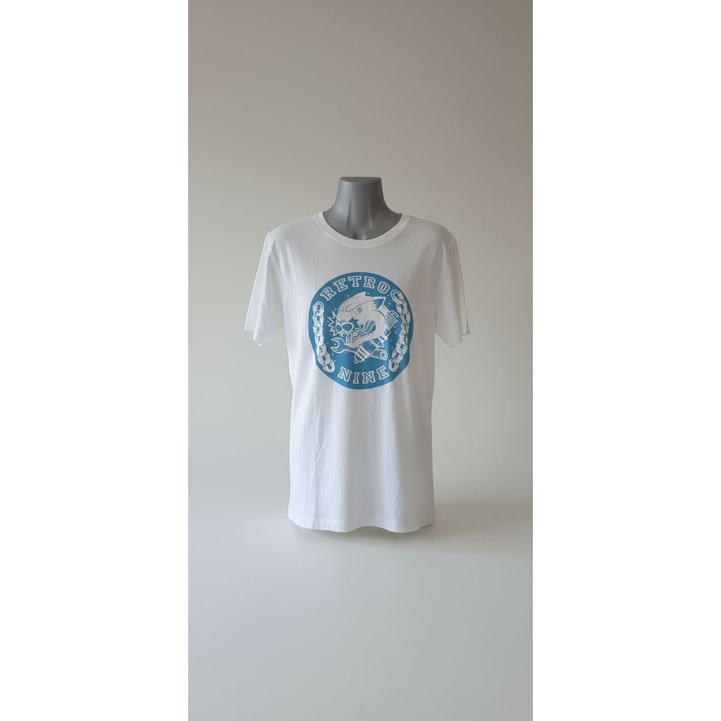 White t-shirt with blue graphic design on a mannequin against a tiled wall.