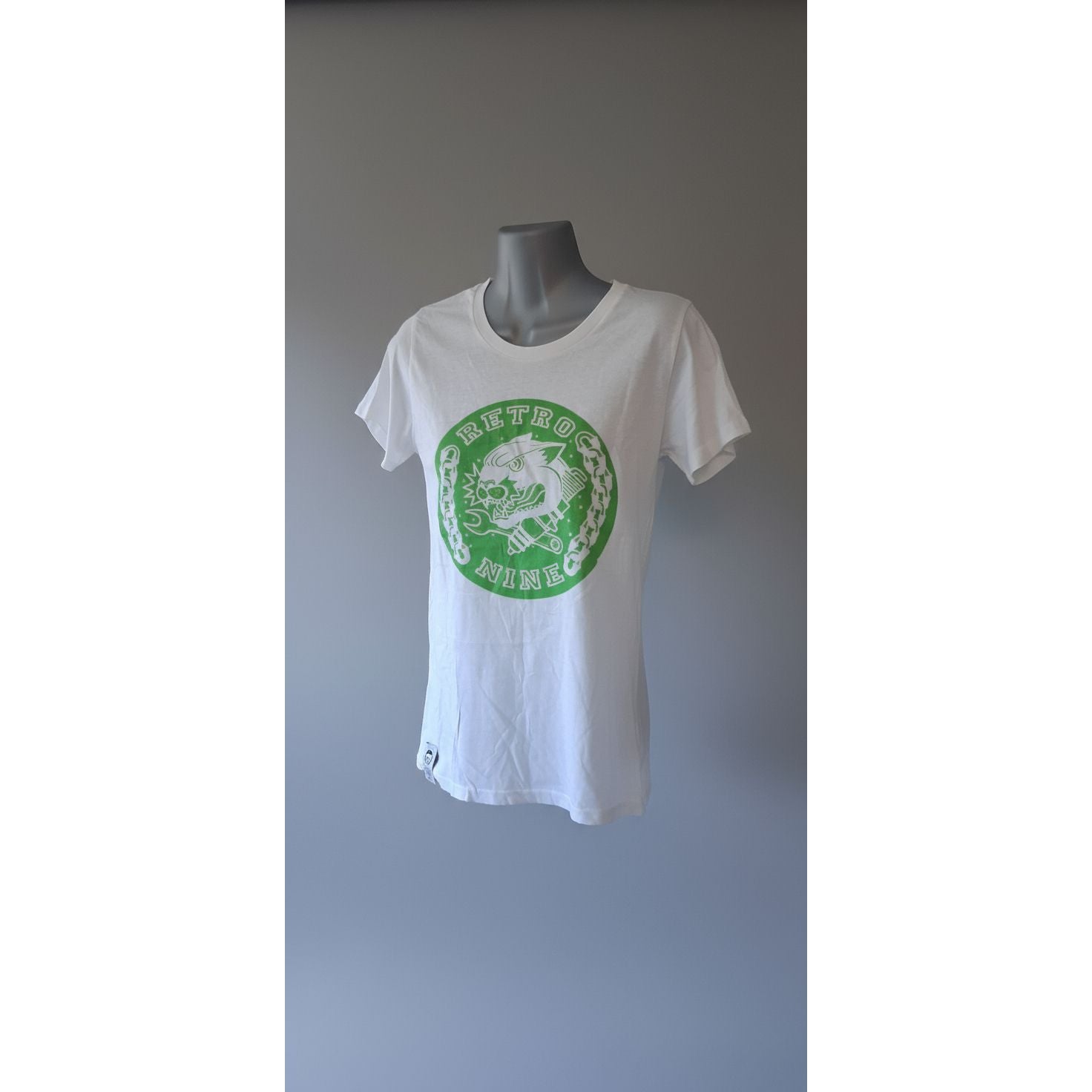 White tank top with green logo on a mannequin against a tiled wall.
