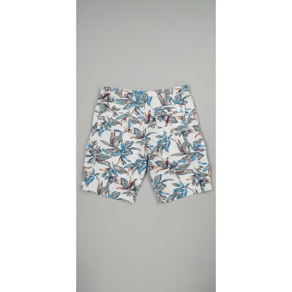 Floral-patterned shorts on a textured floor with a person wearing white socks and gray shoes.