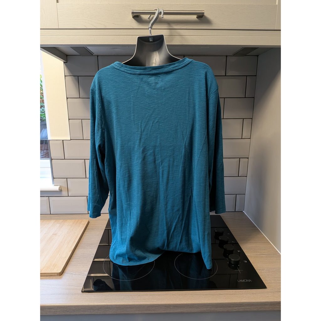 Blue long-sleeve shirt on a hanger over a stove in a kitchen.