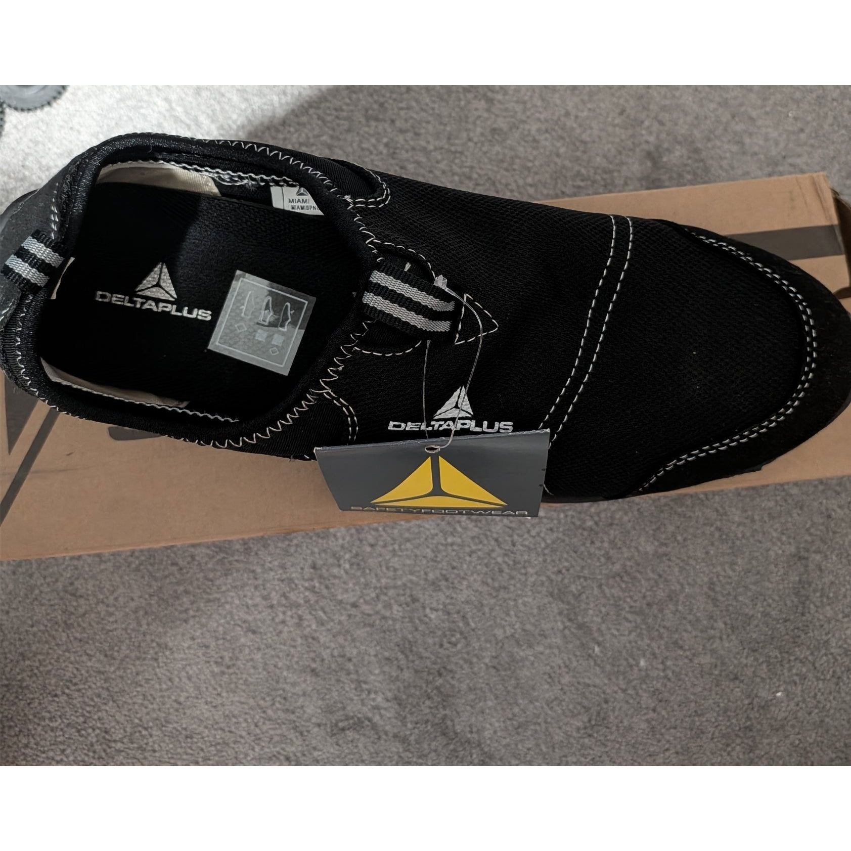 Black shoe with Delta Plus branding on a gray surface