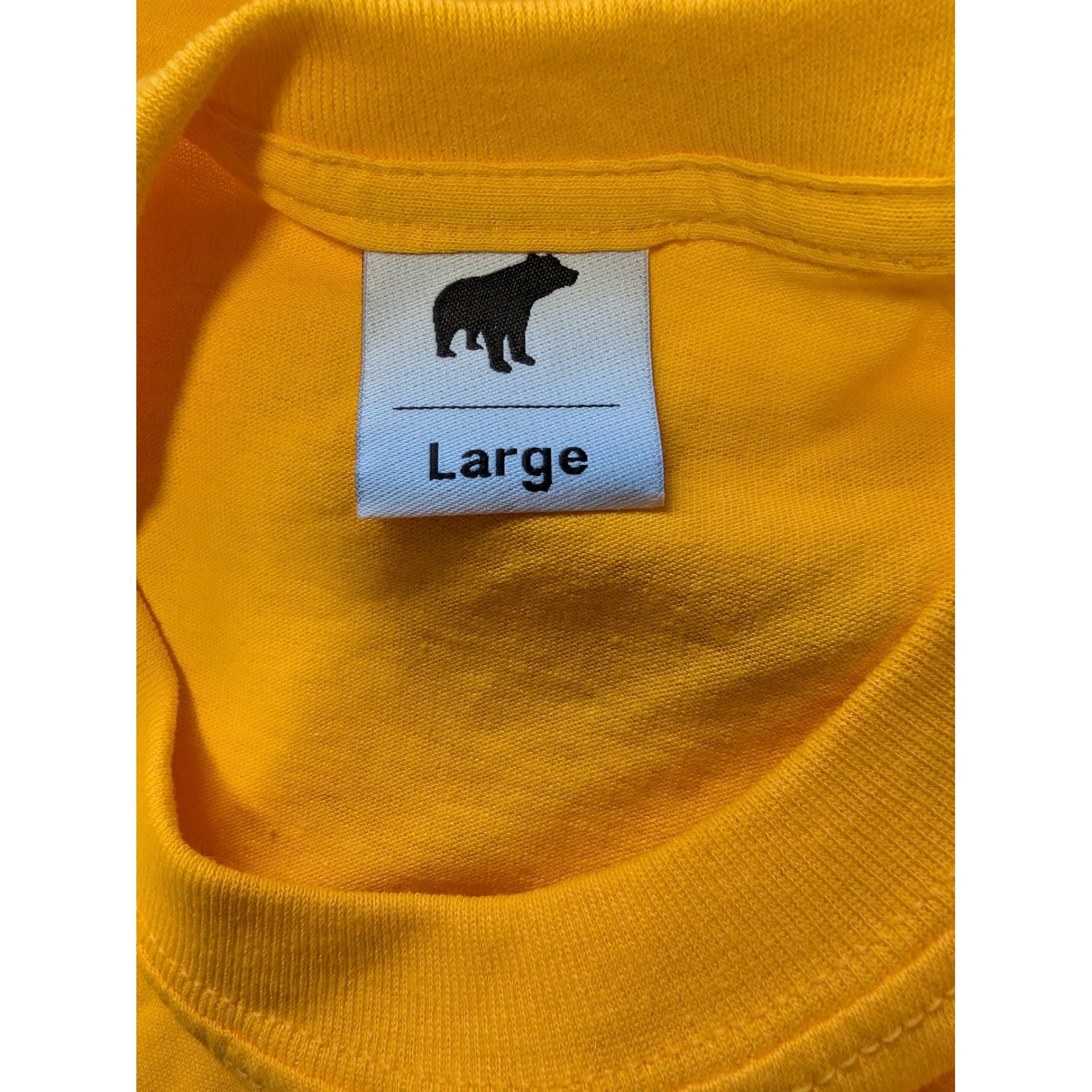 Close-up of a yellow garment with a size label featuring a bear icon and the word 'Large'.