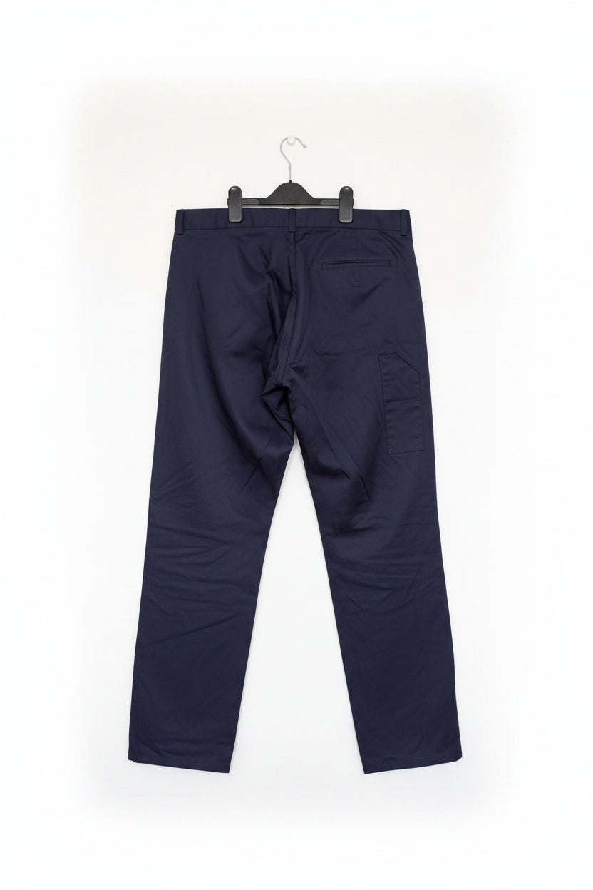 A pair of dark navy blue cropped pants hanging from a black hanger against a white wardrobe door.
