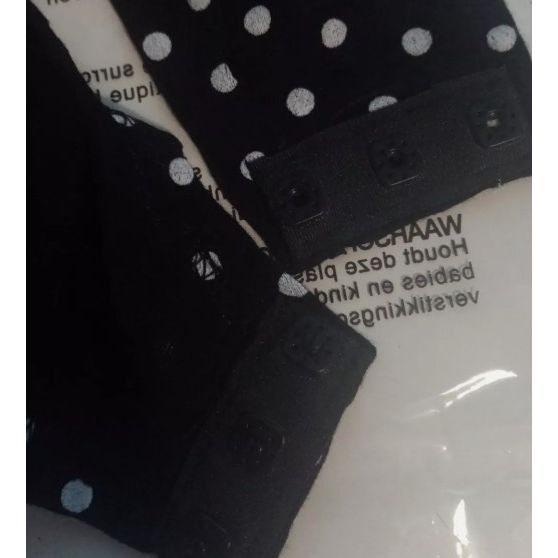 Black polka dot dog sweater with brand label on a white background