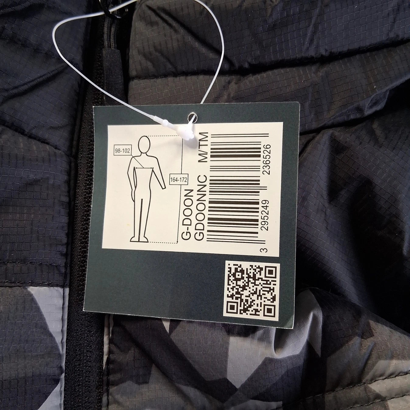 Clothing tag with barcode and QR code on a dark fabric background