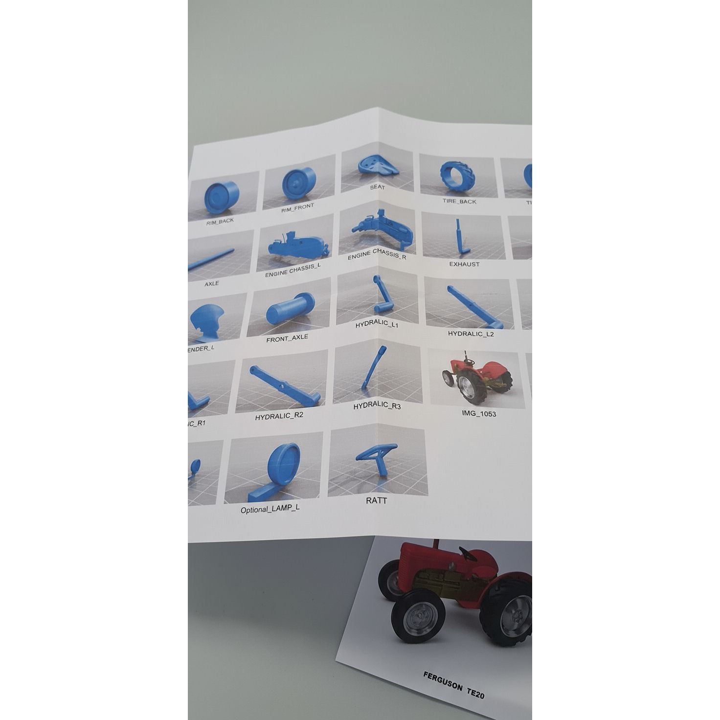 Sheet of blue plastic parts with labels on a white background, placed on a surface.